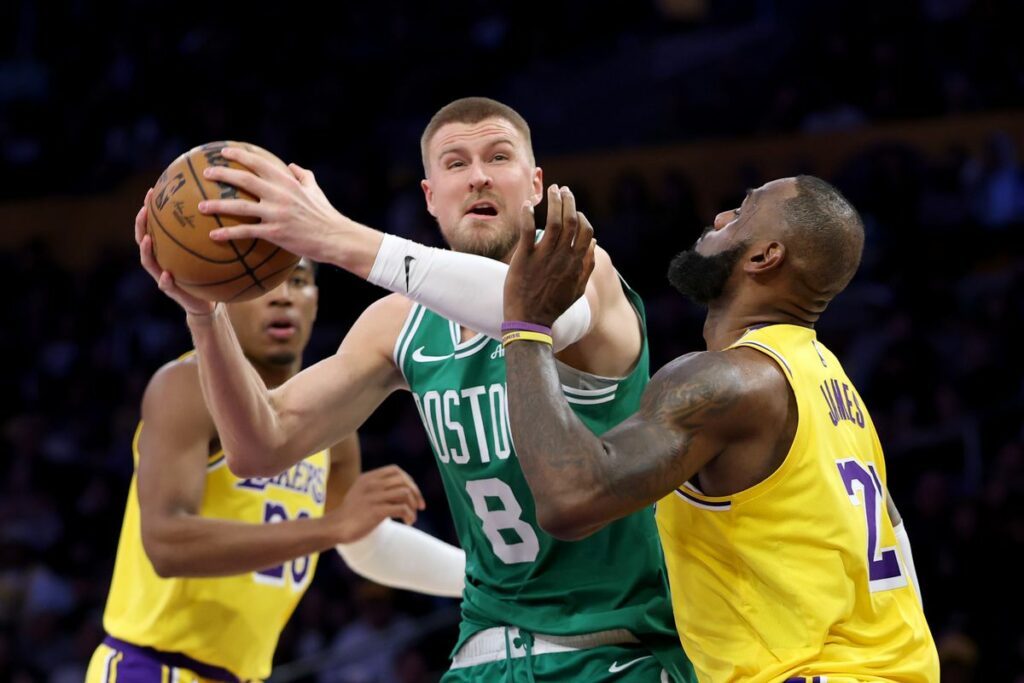 Kristaps Porzingis with the ball defended by LeBron James