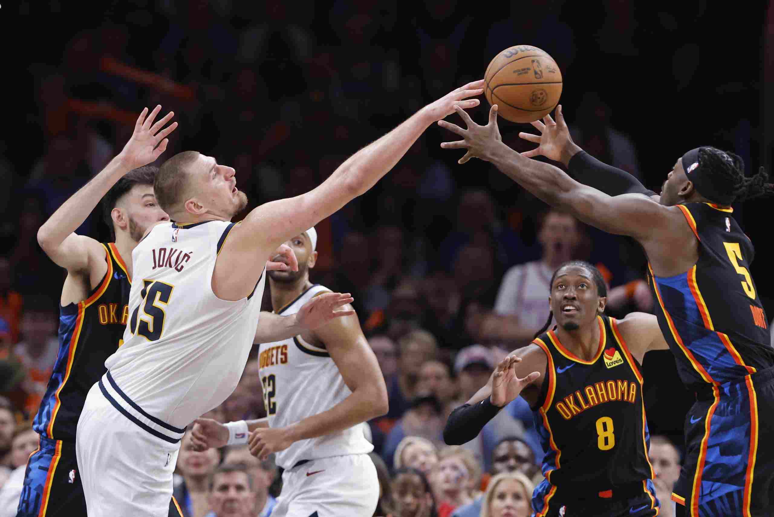 Nikola Jokic and Lu Dort trying to catch a loose ball